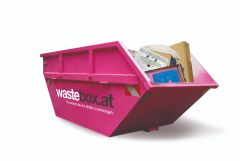 Pinkfarbene wastebox.at-Mulde, gefüllt mit Sperrmüll wie Waschbecken, Kartons und Polstern – 8 m³ Container für sperrige Haushaltsabfälle online bestellen.
